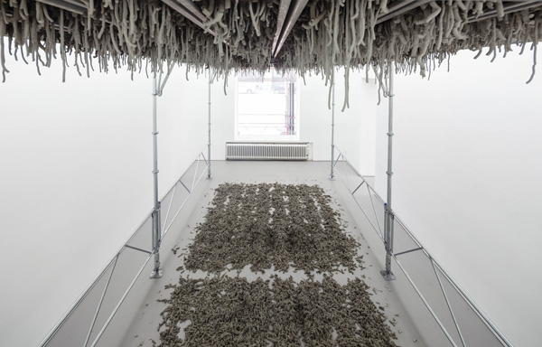 Kristina Matousch, Still Life Production, 2013, scaffolding, steel planks, clay, 3 x 6 x 4 m. During the performance on April 4th, the artist trampled trampled two tonnes of clay through the holes of the platform.