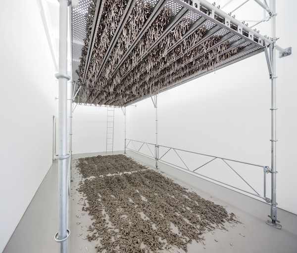 Kristina Matousch, Still Life Production, 2013, scaffolding, steel planks, clay, 3 x 6 x 4 m. During the performance on April 4th, the artist trampled trampled two tonnes of clay through the holes of the platform.