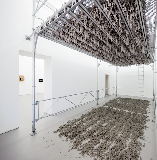 Kristina Matousch, Still Life Production, 2013, scaffolding, steel planks, clay, 3 x 6 x 4 m. During the performance on April 4th, the artist trampled trampled two tonnes of clay through the holes of the platform.