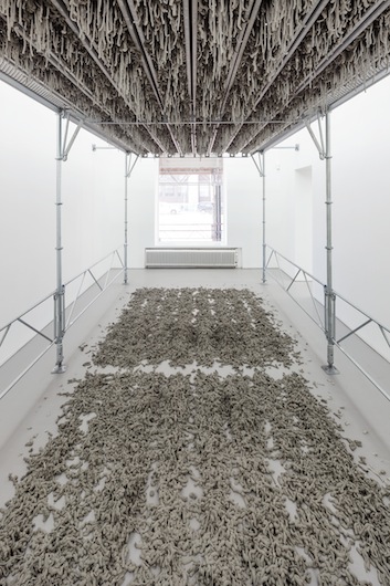 Kristina Matousch, Still Life Production, 2013, scaffolding, steel planks, clay, 3 x 6 x 4 m. During the performance on April 4th, the artist trampled trampled two tonnes of clay through the holes of the platform.