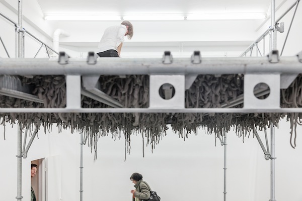 Kristina Matousch, Still Life Production, 2013, scaffolding, steel planks, clay, 3 x 6 x 4 m. During the performance on April 4th, the artist trampled trampled two tonnes of clay through the holes of the platform.