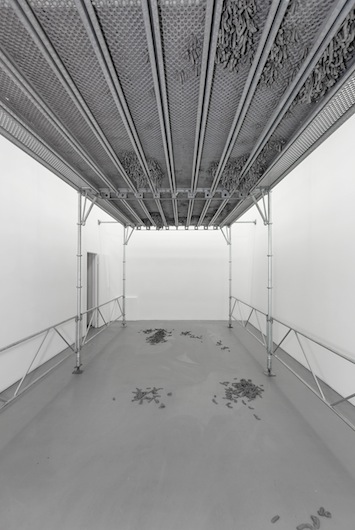 Kristina Matousch, Still Life Production, 2013, scaffolding, steel planks, clay, 3 x 6 x 4 m. During the performance on April 4th, the artist trampled trampled two tonnes of clay through the holes of the platform.