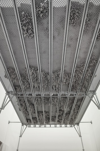 Kristina Matousch, Still Life Production, 2013, scaffolding, steel planks, clay, 3 x 6 x 4 m. During the performance on April 4th, the artist trampled trampled two tonnes of clay through the holes of the platform.