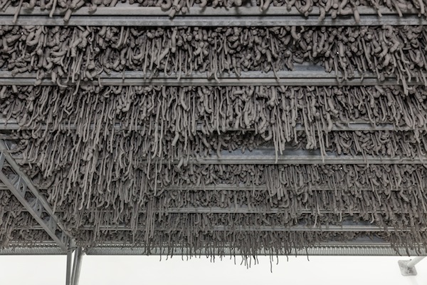 Kristina Matousch, Still Life Production, 2013, scaffolding, steel planks, clay, 3 x 6 x 4 m. During the performance on April 4th, the artist trampled trampled two tonnes of clay through the holes of the platform.